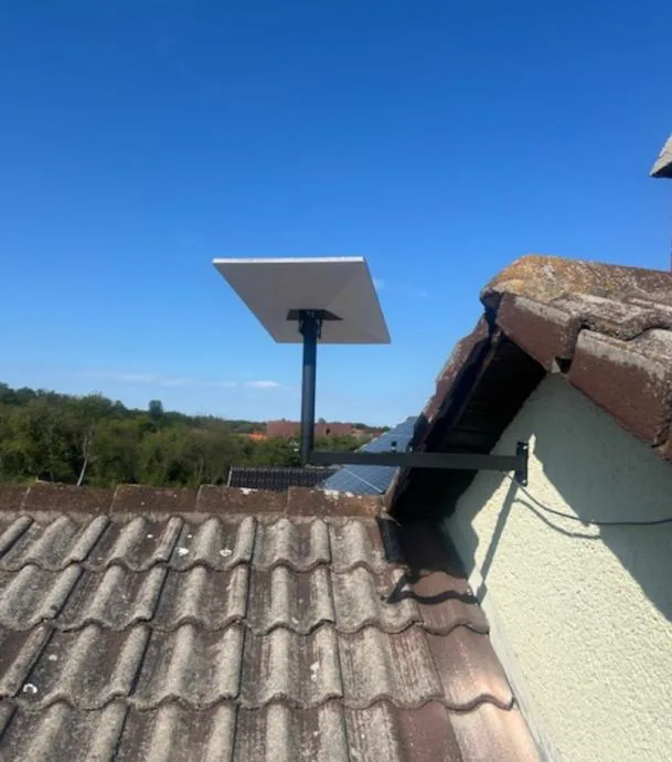 Nosač na zidu uz krov od crijepa, Starlink antena na stupu iznad crijepa