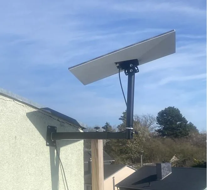 Teleskopski Starlink nosač na zidu kuće, krak izvučen preko ruba krova, antena Starlink Standard na stupu
